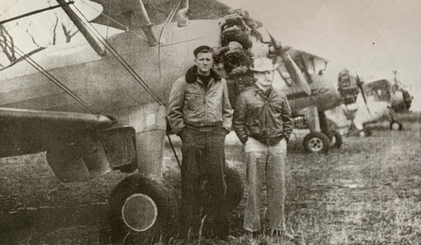 Donald Clark and another individual stand in front of an airplane